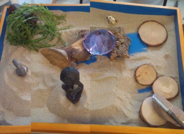 Caja de Sandplay con un prisma morado y un oso escondido