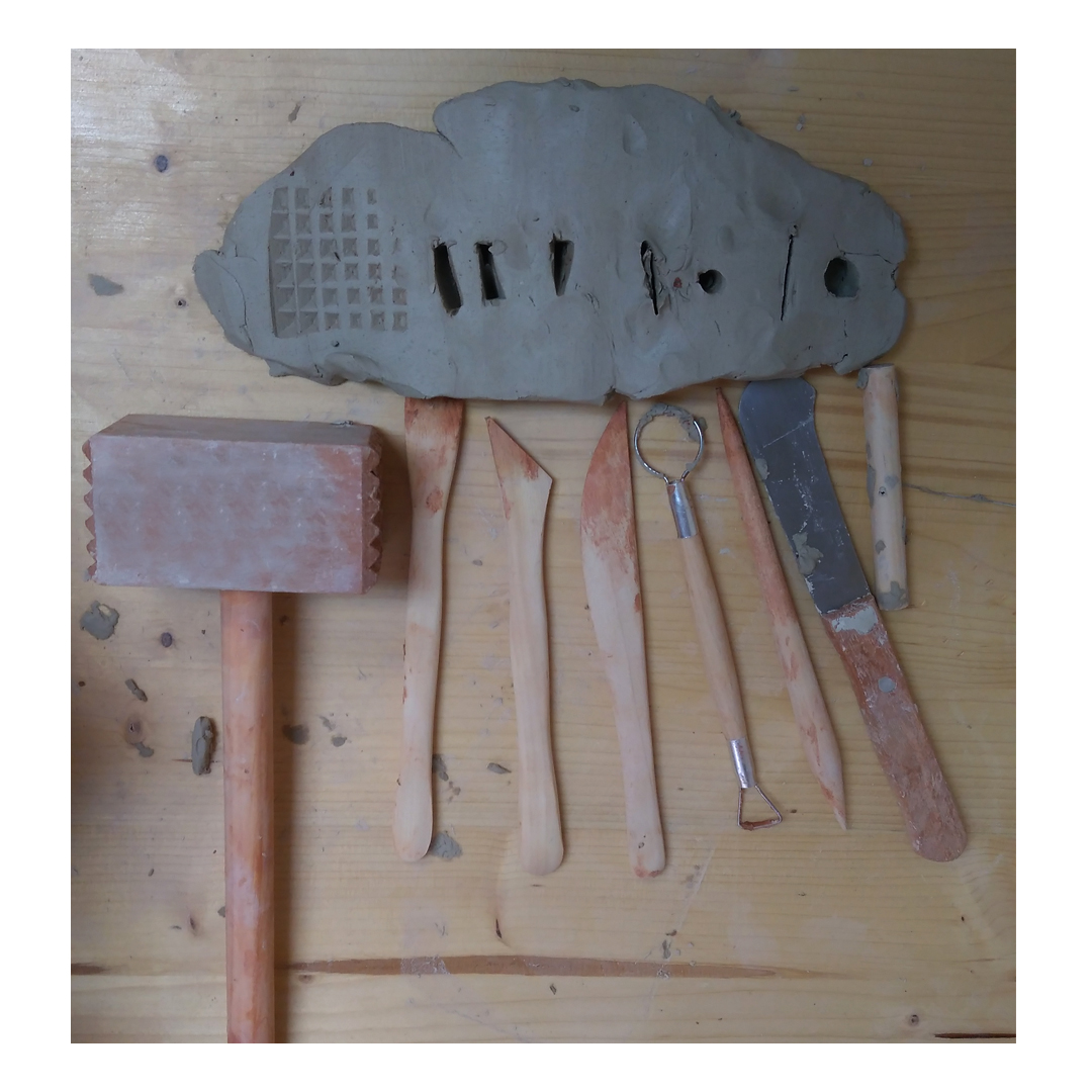 herramientas para trabajar la arcilla y un trozo de arcilla plano en las que se ven las muescas que dejan esas herramientas
